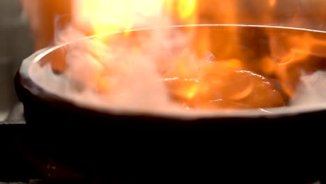 cooking shrimps in frying pan with flame