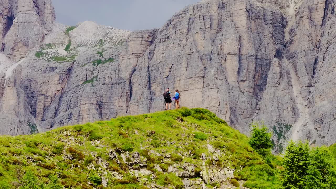 Drone orbiting hikers on Col de la Puina as bird flies past mountain cliffs