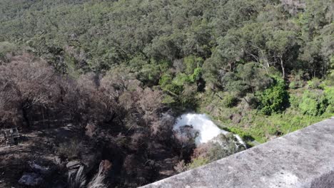 View-from-the-top-of-the-dam-wall-down-to-the-valley,-where-two-turbines-releasing-water-with-a-lot-of-pressure