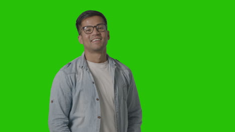 Portrait-Of-Casually-Dressed-Smiling-Young-Man-Wearing-Glasses-Against-Green-Screen-