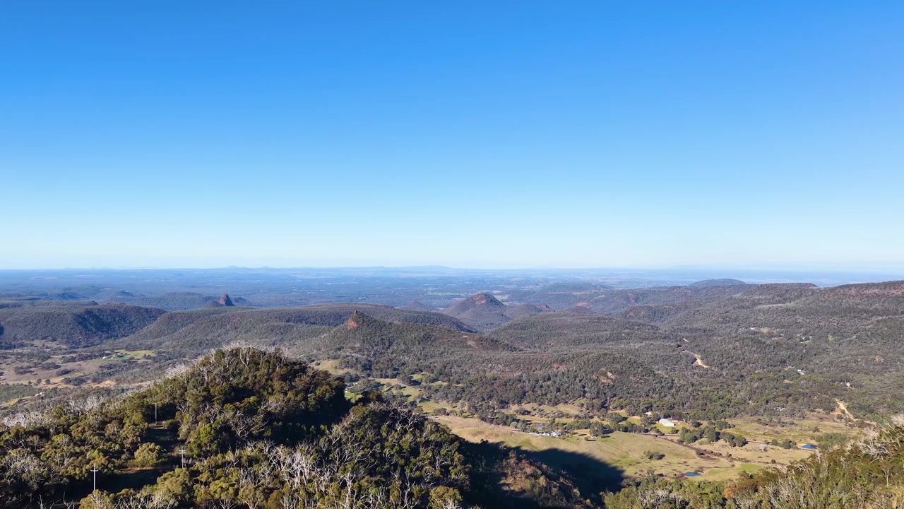 Panoramaudsigt over bølgende bakker og dal under klar blå himmel