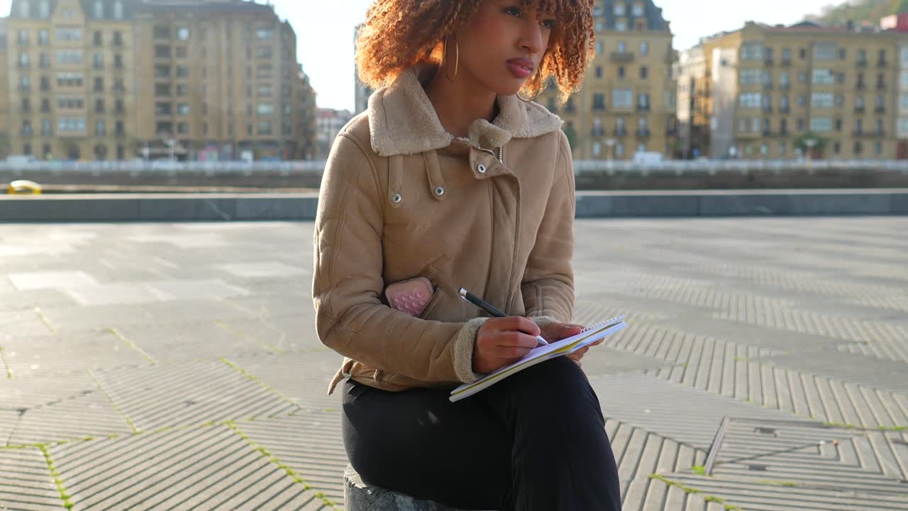 Woman writing in a notebook outdoors in the city