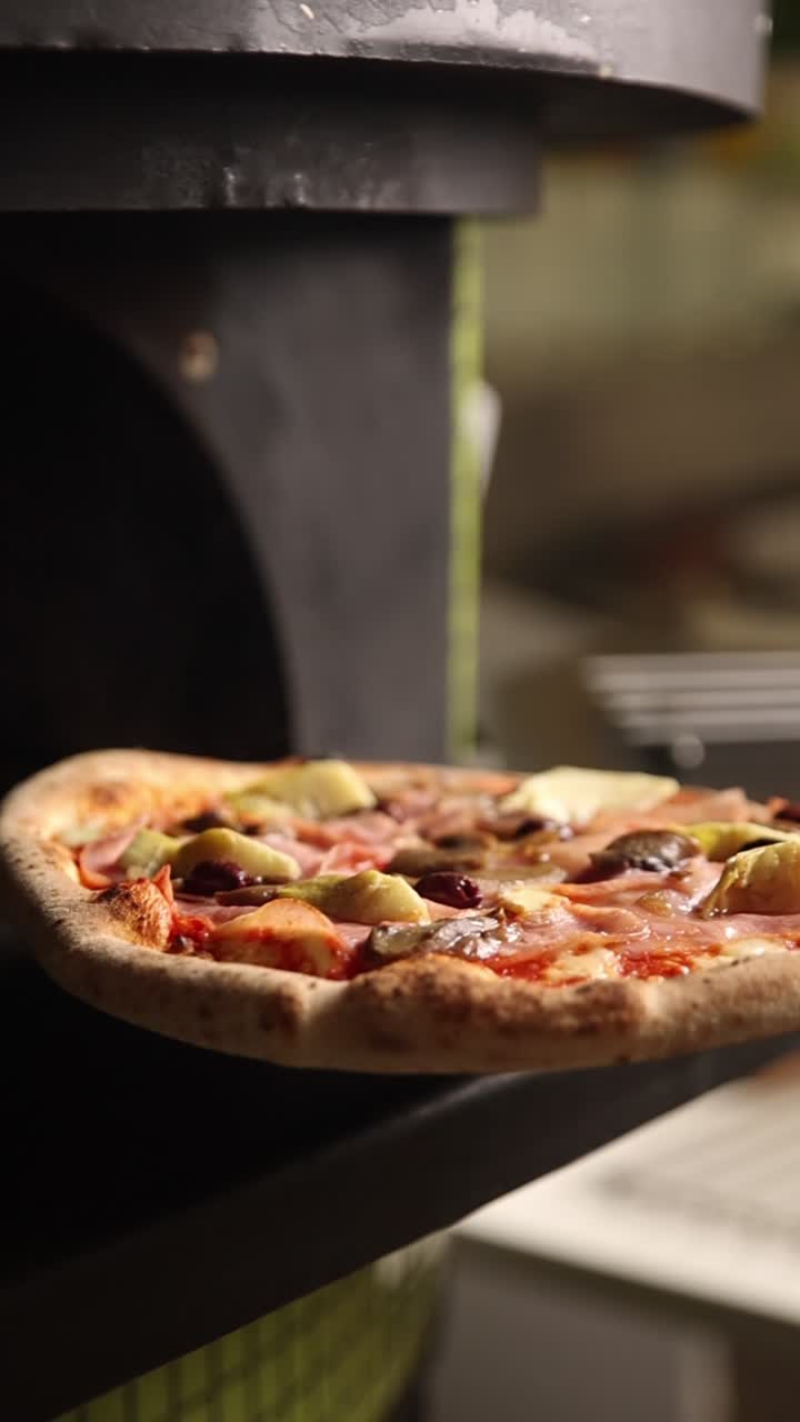 Pizza deliziosa con prosciutto, carciofi e olive in cottura in un forno caldo
