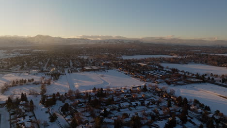 Drone-shot-of-the-sun-setting-over-the-Rocky-Mountains-in-Denver,-CO-on-a-snowy-winter-day