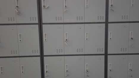pan right showing locked storage lockers with keys in indoor corridor, flat lighting