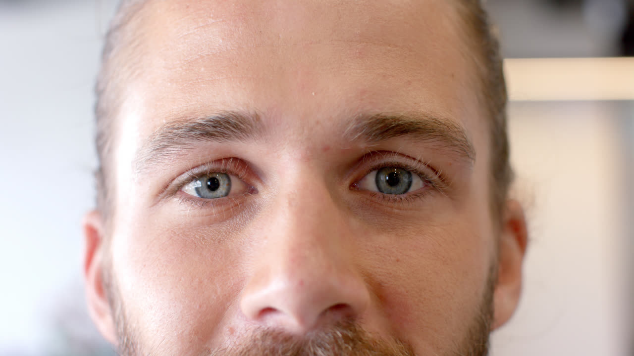 retrato en primer plano de un feliz hombre de negocios caucásico abriendo los ojos azules sonriendo en cámara lenta