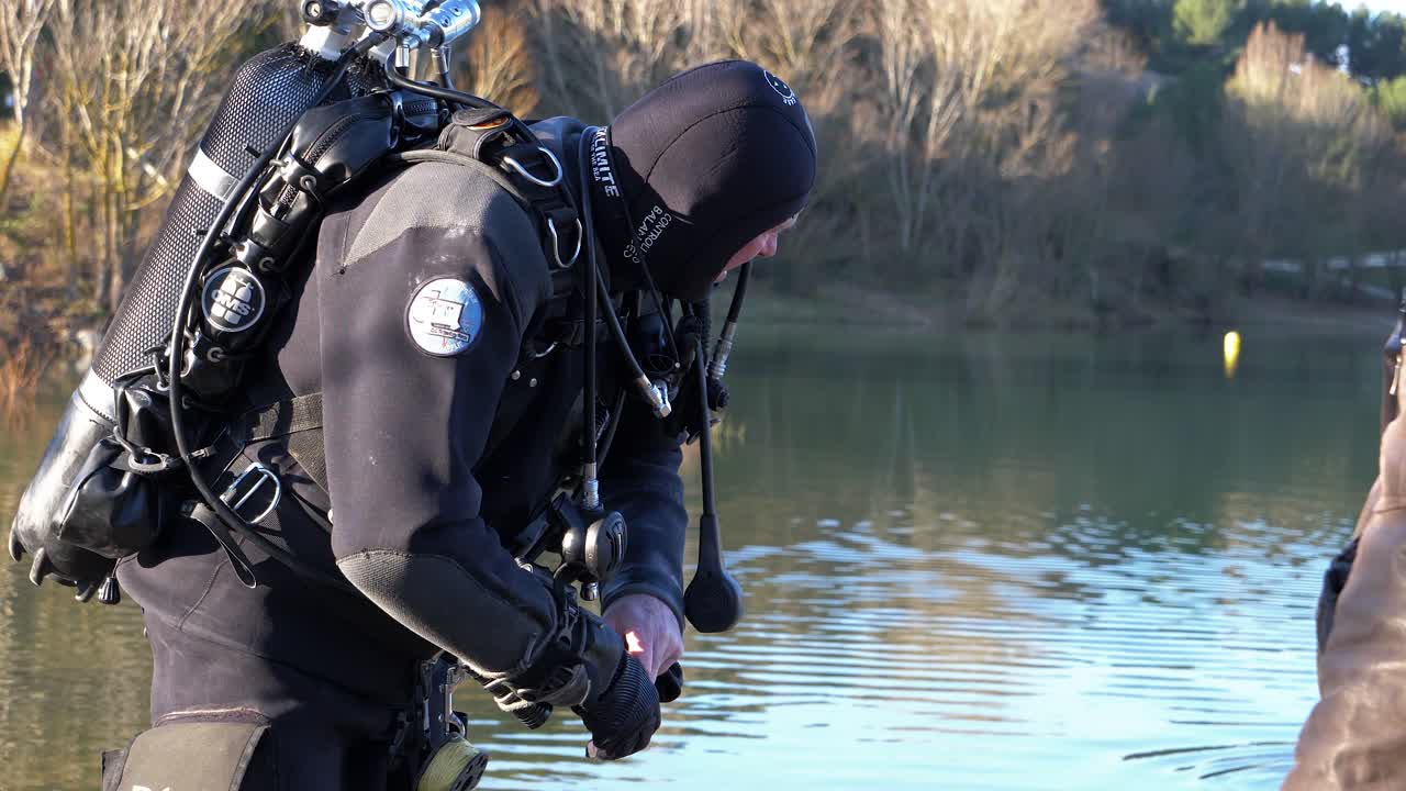 A diver out of the water puts on his black gloves