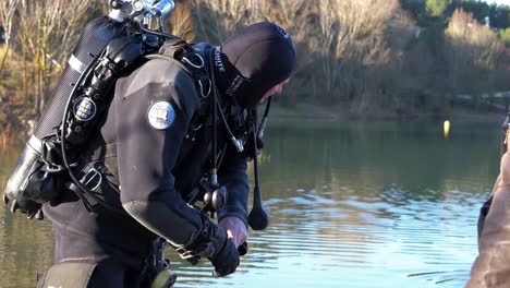 a diver out of the water puts on his black gloves