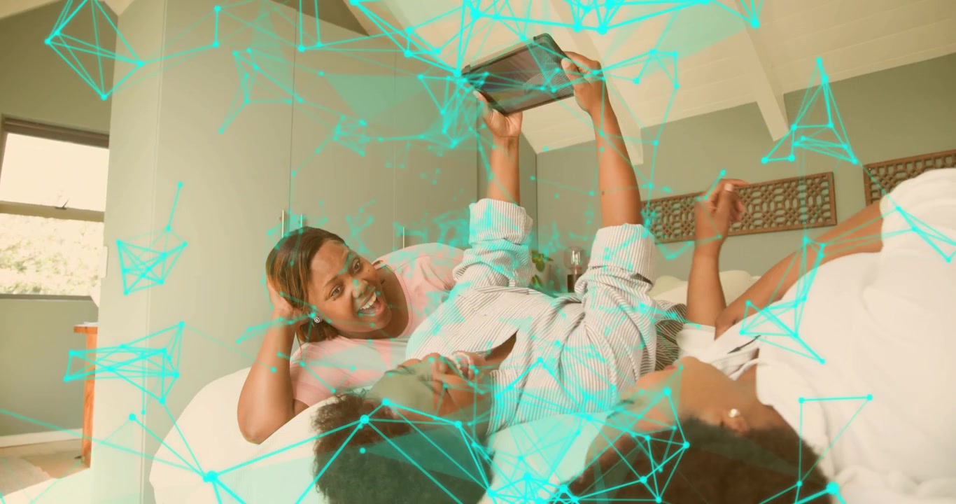 Couple reclining on bed tapping tablet screen and sharing laughter while exploring tech interface