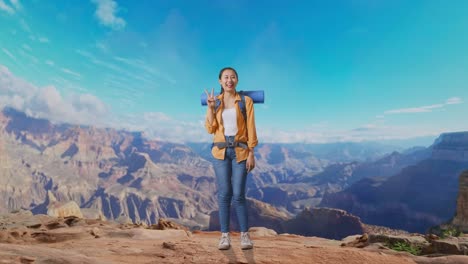 full body of asian female hiker with mountaineering backpack smiling and showing peace gesture while traveling at the top of mountain