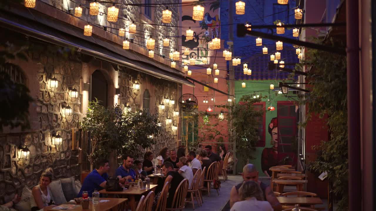Bustling outdoor cafe bar (taverna) at night, Lesbos Island, Handheld gimbal shot