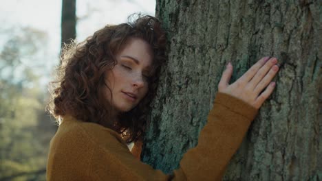 caucasian adult woman bonding to tree in forest.