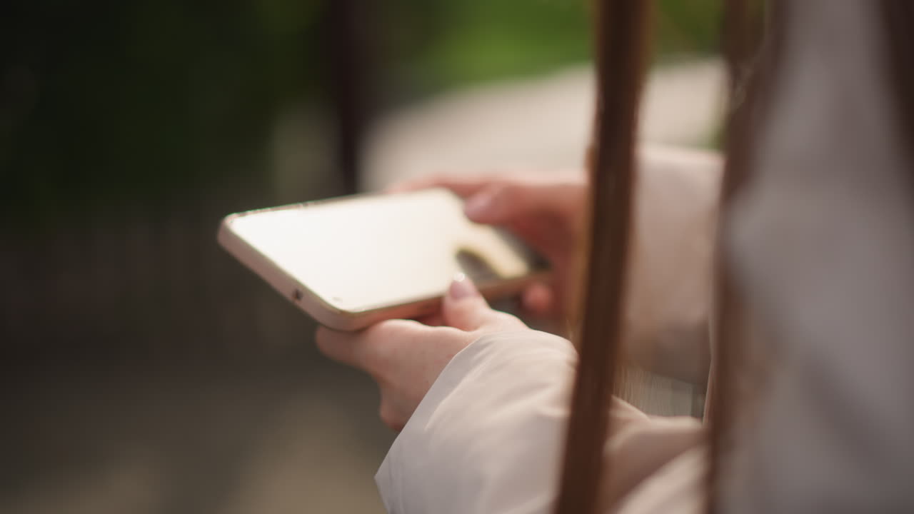 Primo piano di mani che tengono un blocco note all'aperto, donna con un cappotto leggero che sfoglia le pagine sotto la luce soffusa del sole, copertina in legno con bordo a spirale, sfondo bokeh del parco leggermente sfocato, gesti delicati con la punta delle dita, intimo