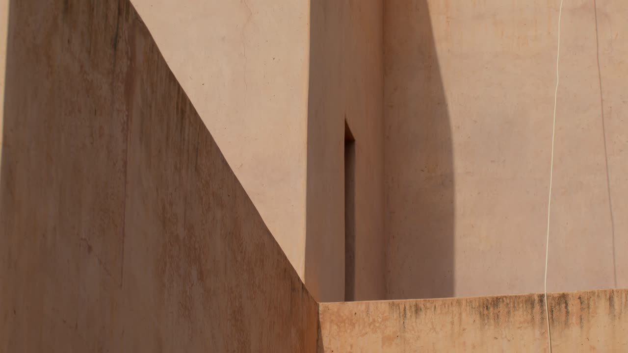 Close-up shot emphasizing geometric patterns in Moroccan architecture with strong sunlight casting dynamic shadows and light in Marrakech, Morocco