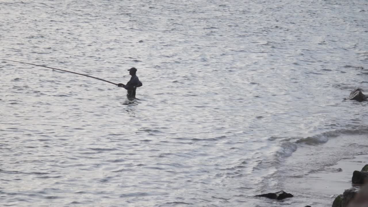 pescador de pie en lo alto de la cadera en el mar sosteniendo caña de pescar acción silueta escénica tarde tiempo cámara lenta b roll clip, fuerte holandés de galle, sri lanka