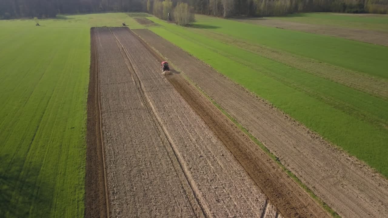luftlandwirtschaftliches landwirtschaftskonzept roter traktor, der das land in einem grünen feld pflügt