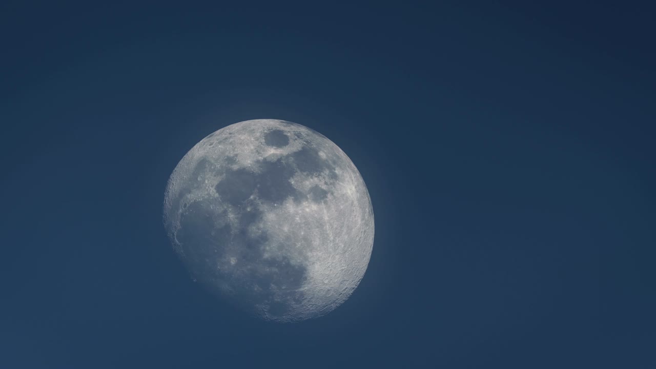 Large close-up of 3/4 gibbous moon traversing evening sky - time lapse
