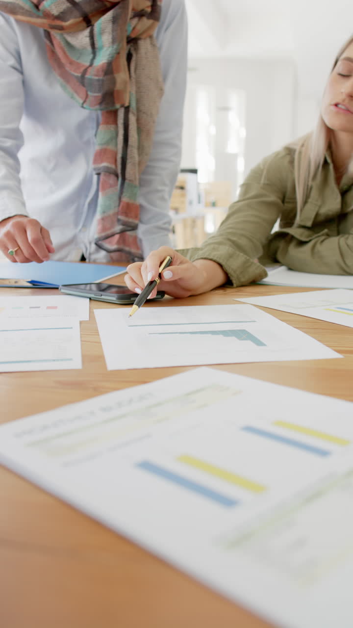 Vertical video of busy diverse business people discussing documents in slow motion