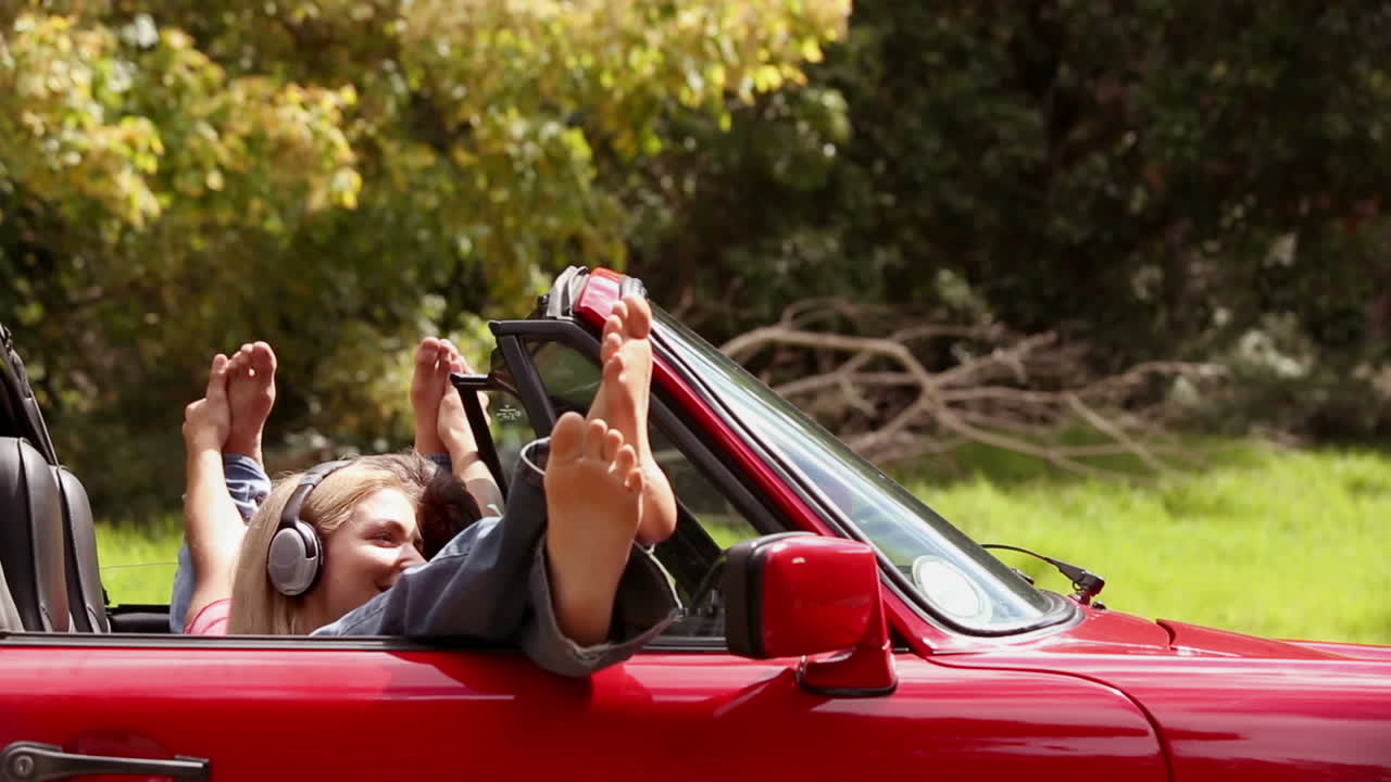 chicas escuchando música en un coche rojo