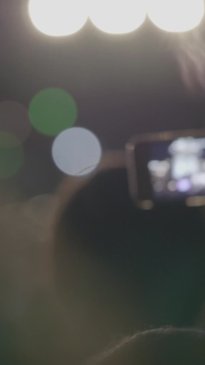 Person Recording a Live Concert with a Smartphone at Night