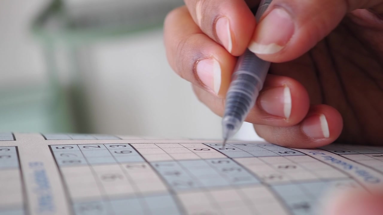 Persona che risolve un Sudoku con una penna