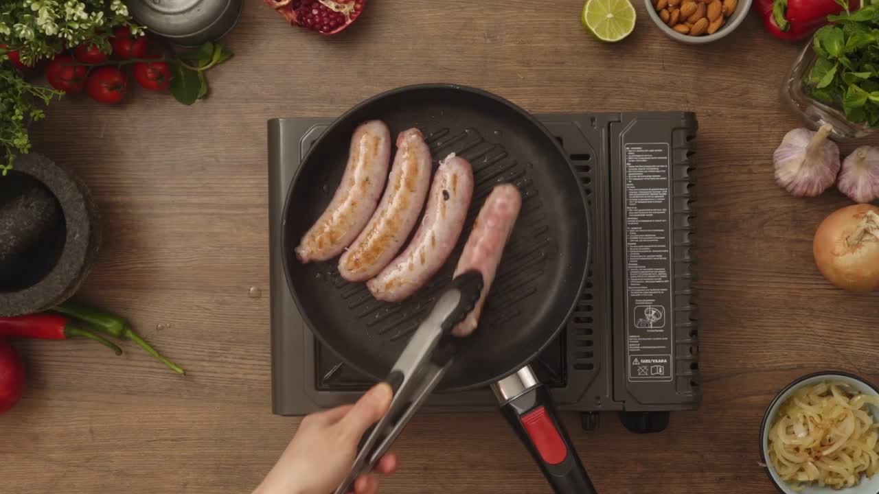 Crop person turning homemade sausages frying in pan