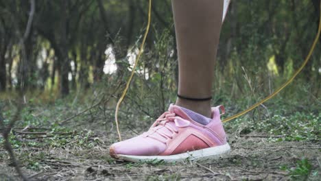 athletic beautiful woman exercises with jump, skipping rope in the forest