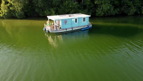 small house boat on a green lake next to a forest in brandenburg, germany