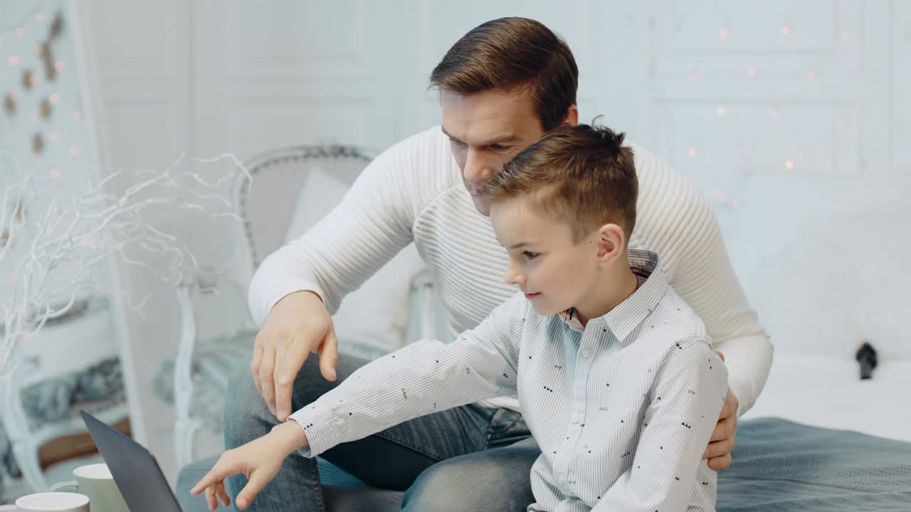 hombre feliz hablando con un niño cerca de un cuaderno en una casa privada.