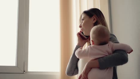 Mamá-Sosteniendo-A-Un-Bebé-Hablando-Por-Su-Teléfono-Celular