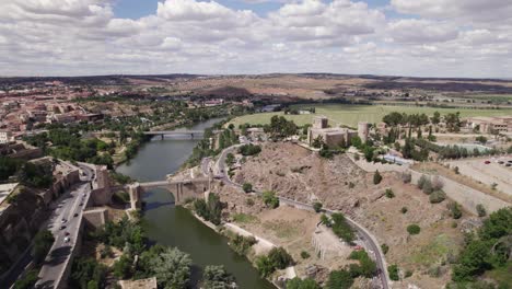 aerial view of castle of san servando with alcantara bridge over river tagus on clear day with fluffy white clouds overhead