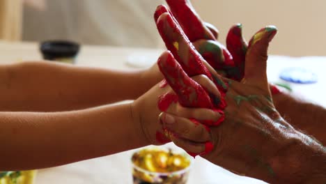 intertwined hands and fingers of child and adult with red paint on them for connection and cooperation concept