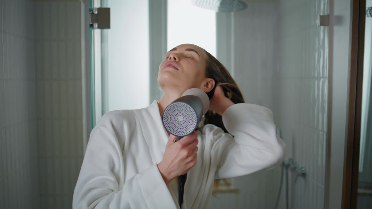 Young woman drying hair at home closeup. Serene lady getting ready in morning