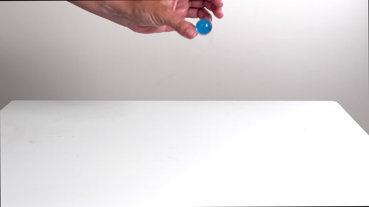Blue Bouncy Ball Dropped and Bouncing on White Surface