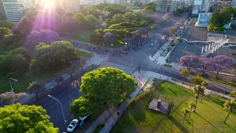 Dolly-En-Vista-Aérea-De-Un-Grupo-De-Ciclistas-Con-Una-Toma-épica-De-Los-Rayos-Del-Sol,-Plaza-Llena-De-árboles-Alrededor,-Barrio-Recoleta