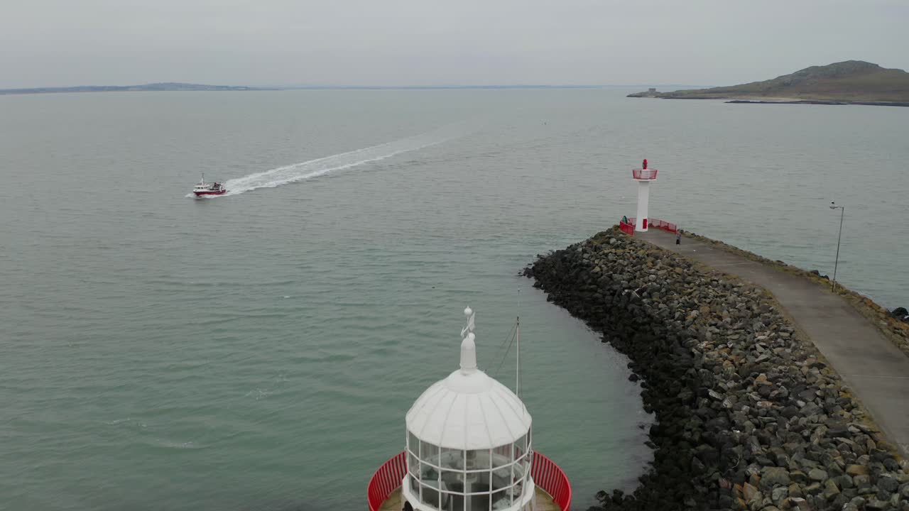 Cinematic aerial descent. Boat approaching Howth's harbour. Ireland