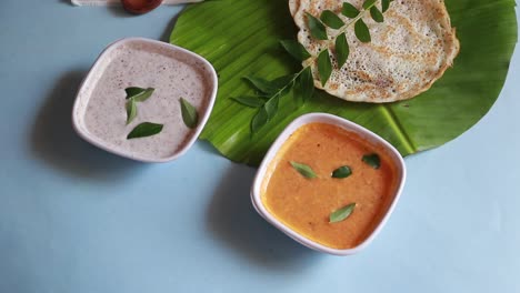 rotating set dosa is a 'set' of 2 dosas topped with butter or ghee and chutney on blue background