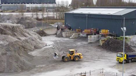 aerial view, bulldozer preparing to dump material into loader truck on uk power station coal resource site, tilting up