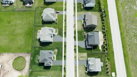 aerial shot of a neighborhood with modern family homes on one side and a not so busy urban road on the other side