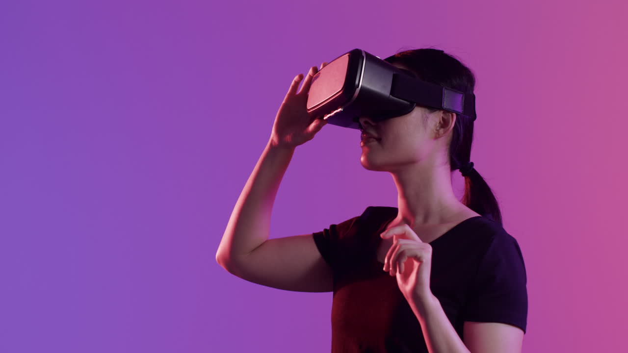 donna asiatica che usa le cuffie vr, touch screen su sfondo viola, spazio di copia, slow motion