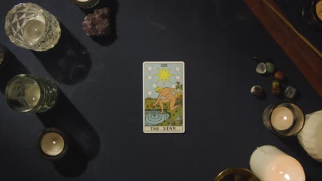 toma aérea de una persona que da lectura de cartas del tarot colocando la carta de la estrella en la mesa