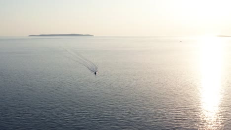 Toma-Aérea-De-Una-Lancha-A-Toda-Velocidad-Frente-A-La-Costa-De-La-Isla-De-Losinj,-Croacia