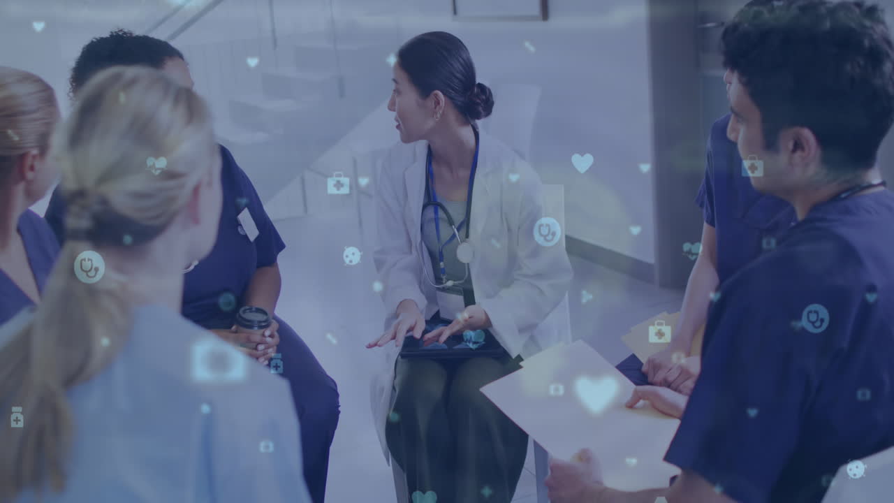 Animation of medical icons over asian female doctor talking with diverse colleagues in hospital