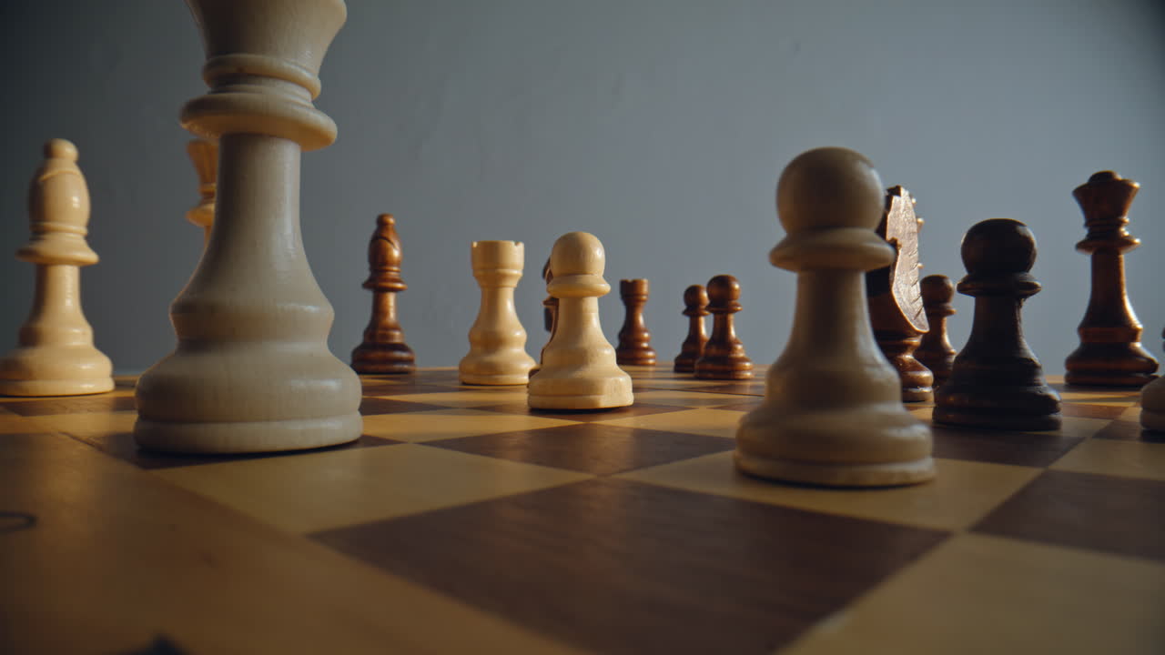 Person shifting pawn figure on checkered platform between opposing units closeup