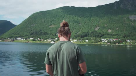 norwegian guy fishing on the lakeshore near medby village, senja, norway