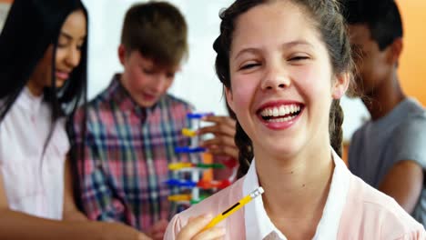 retrato de una colegiala sonriente sosteniendo un lápiz en el aula