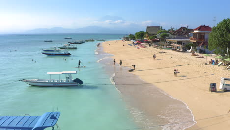 nusa lambogan beautiful sunset beach with crystal clear ocean and white sand, sailing boats and palms