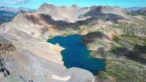 Pristine-Lake-Under-Hills-of-Rocky-Mountains-National-Park,-Colorado-USA,-Drone-Aerial-View