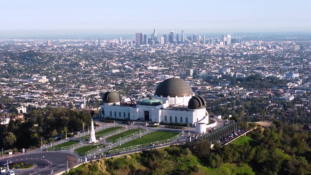 Osservatorio Griffith che si affaccia sul centro di Los Angeles, California. Orizzonte della città in una giornata limpida e soleggiata. Prato recintato senza persone su erba perfetta.