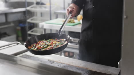 Caucasian-male-chef-frying-vegetables-in-a-pan-in-kitchen,-slow-motion